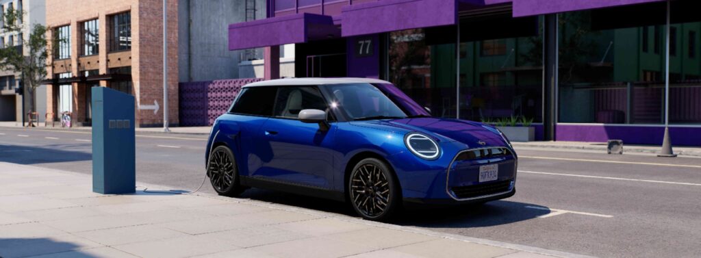 MINI Cooper Electric in blau auf Straße an öffentlicher Ladestation