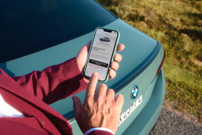 Mann hält Mobiltelefon in der Hand und hat My BMW App geöffnet