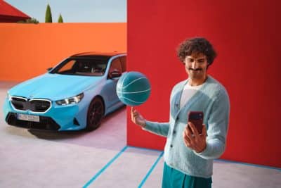 BMW Service mit Proactive Care - Mann mit Basketball und Smartphone in der Hand und einem BMW in der linken Ecke