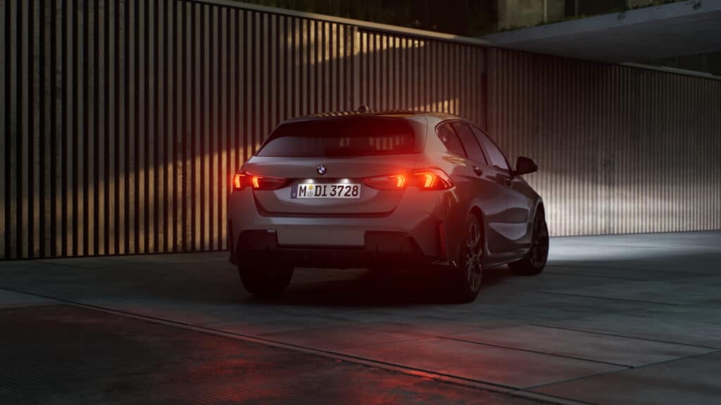 Grauer BMW 1er von hinten in Dunkelheit. Die Heckscheinwerfer leuchten rot.