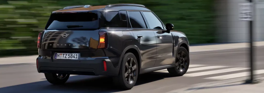 MINI Countryman Blackyard in fahrender Bewegung auf Straße von hinten.