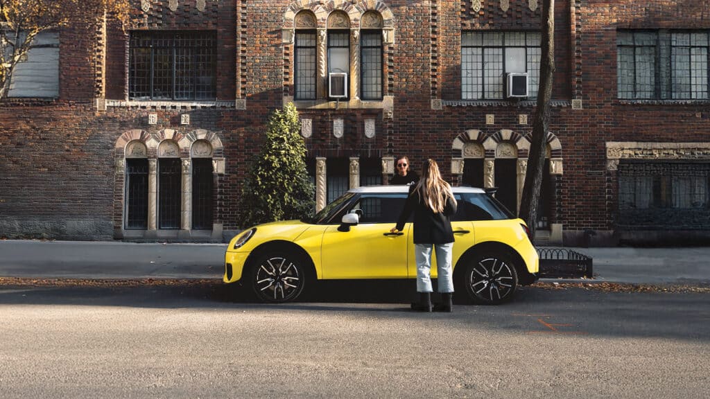 Unterberger MINI Junge Gebrauchte: Frau mit blonden Haaren will grade in einen gelben MINI 5-Türer einsteigen.