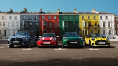 MINI Next - MINI Fahrzeugrange in bunten Farben vor Gebäuden