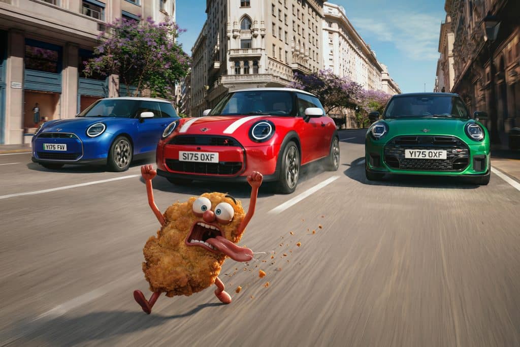 MINI Schnitzeljagd Probefahrtaktion - ein blauer, ein roter und ein grüner MINI fahren hinter einem panisch blickendem Schnitzel hinterher