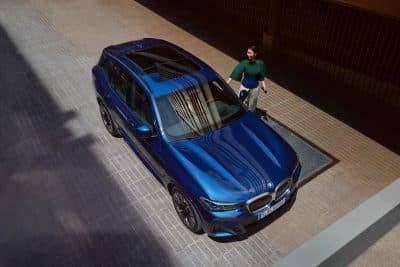 Service Inclusive Kunde läuft in der Nähe eines BMW IX3